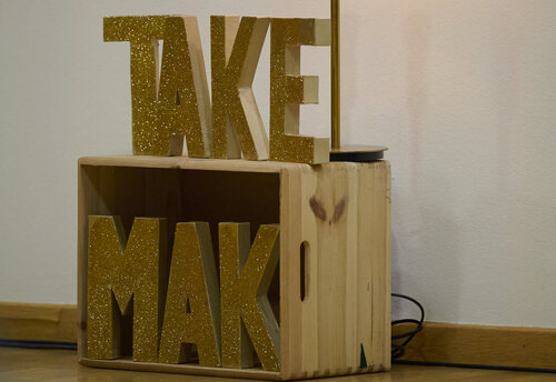 eine Holzkonstruktion mit der Aufschrift „TAKE MAK"