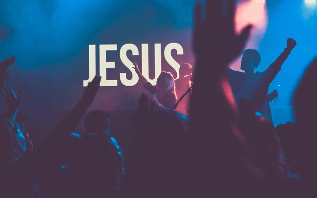 Bild zeigt feiiernde Jugendliche mit dem Wort Jesus im Hintergrund