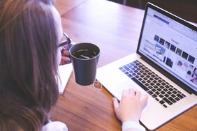 Frau am Schreibtisch mit Laptop und Kaffee